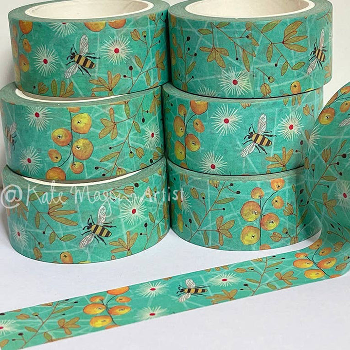 Rolls of aqua decorative tape with floral and bee pattern on a white background