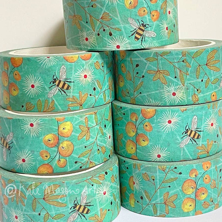 Stack of turquoise washi tape with bee and floral pattern on a white background