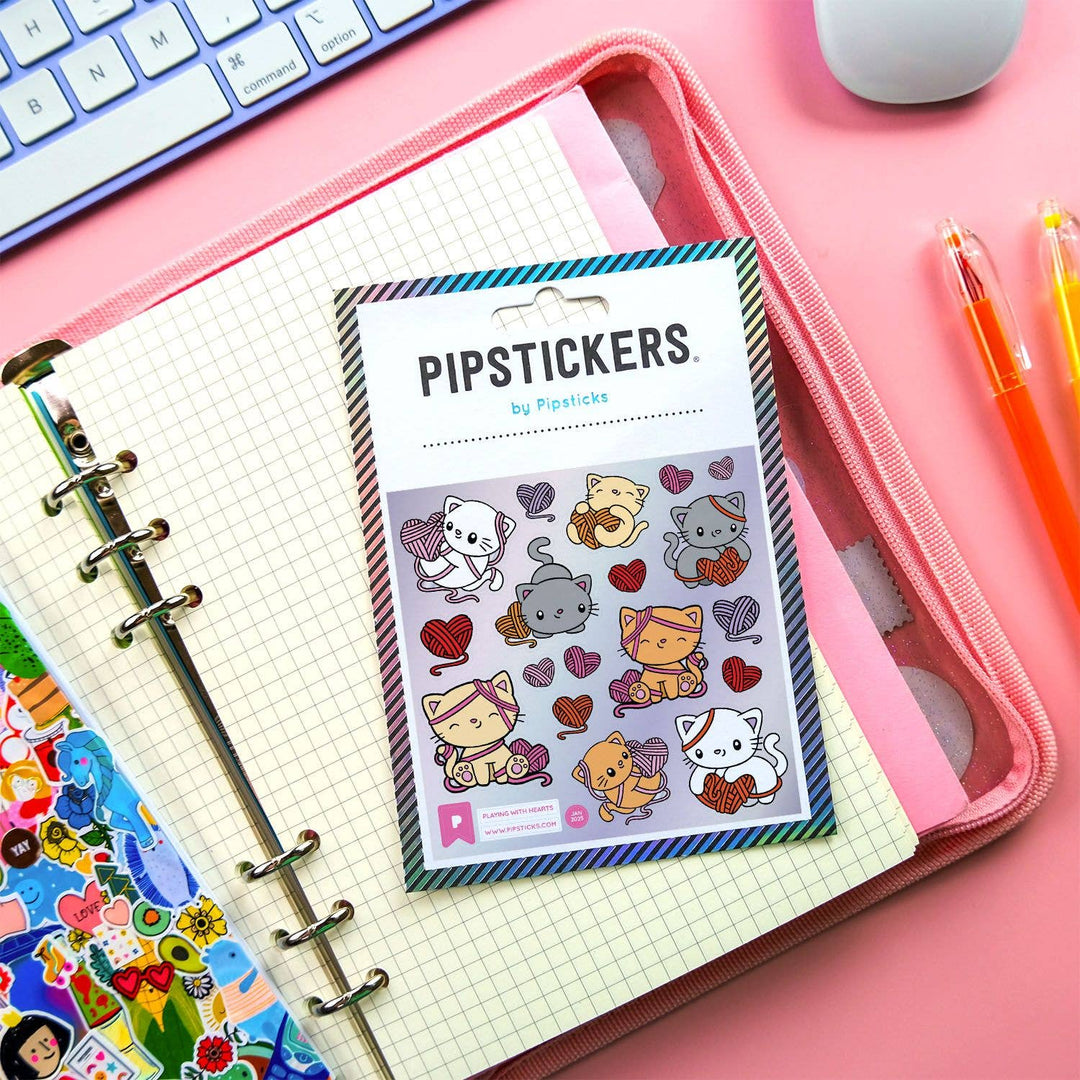 Pack of PipStickers with cartoon animals and hearts on a pink desk with stationery items.