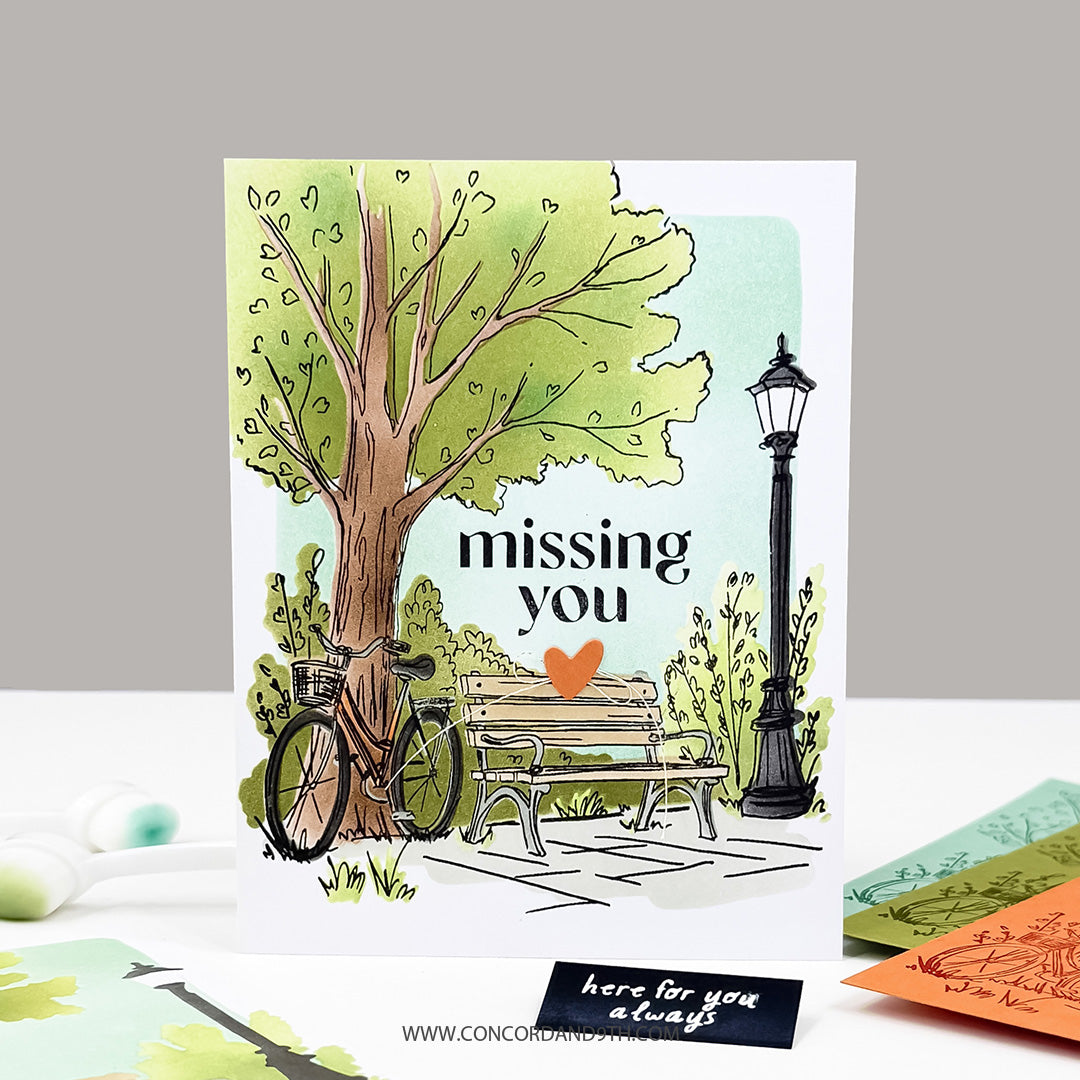 A card made with the Concord & 9th Park Bench set: a watercolour park scene with a tree, bicycle, bench and lamp post, and 'missing you'.