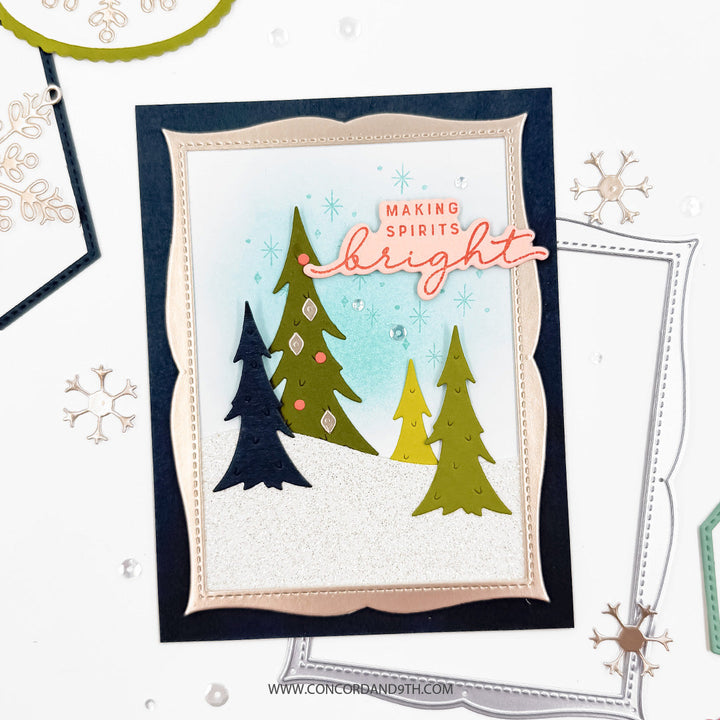 Concord & 9th Assorted Frames Dies — a scalloped rectangle frame around a stamped scene of layered pine trees on a snowy hill, with a "Making Spirits Bright" sentiment.