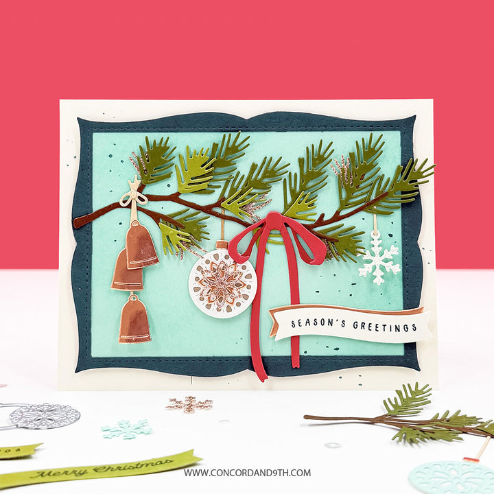 Concord & 9th Holiday Trimmings Dies — a pine branch with hanging bell and medallion ornaments and a red bow, with a "Season's Greetings" sentiment on a teal-and-navy scalloped frame.