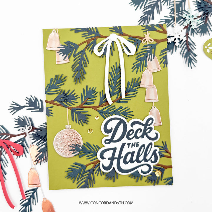 Concord & 9th Holiday Trimmings Stamp Set — a pine branch with hanging bells and a medallion ornament on an olive background, with a white bow and "Deck the Halls" sentiment.