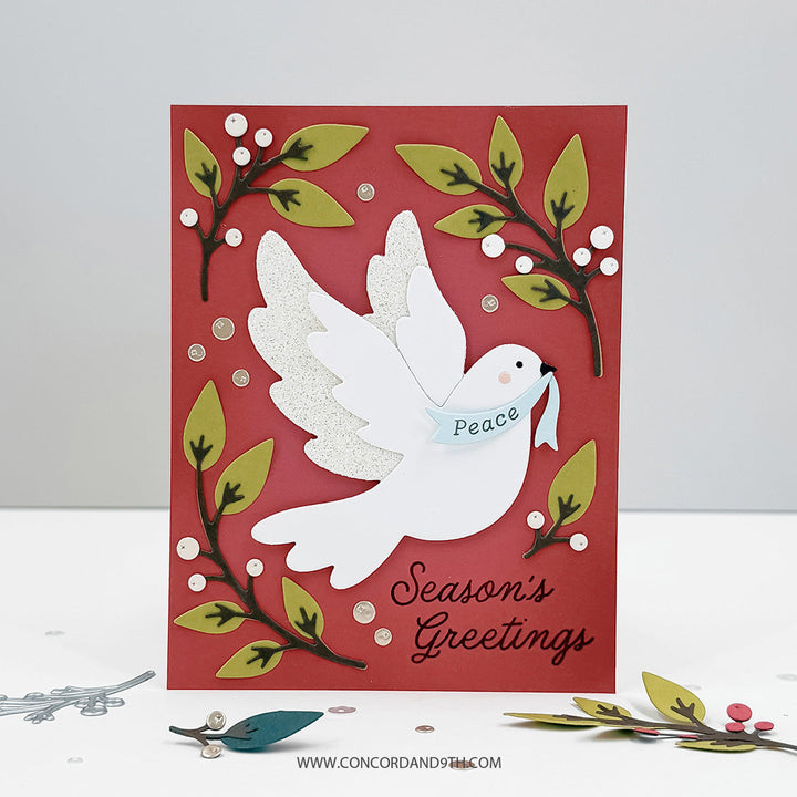 Concord & 9th Peaceful Dove Dies — a glitter-winged dove carrying a "Peace" banner on a red card, with leafy berry-branch die-cuts and a "Season's Greetings" sentiment.