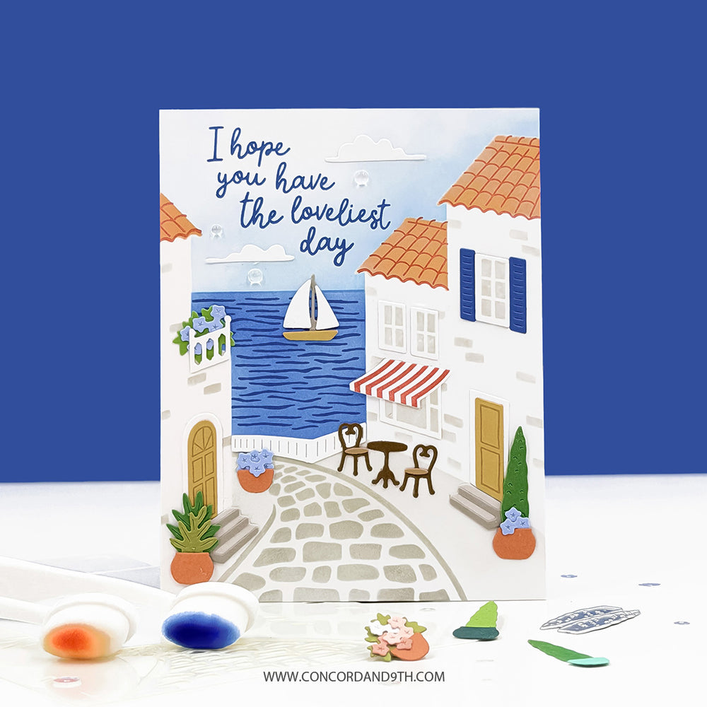 Greeting card with a coastal scene and text 'I hope you have the loveliest day' on a blue background.