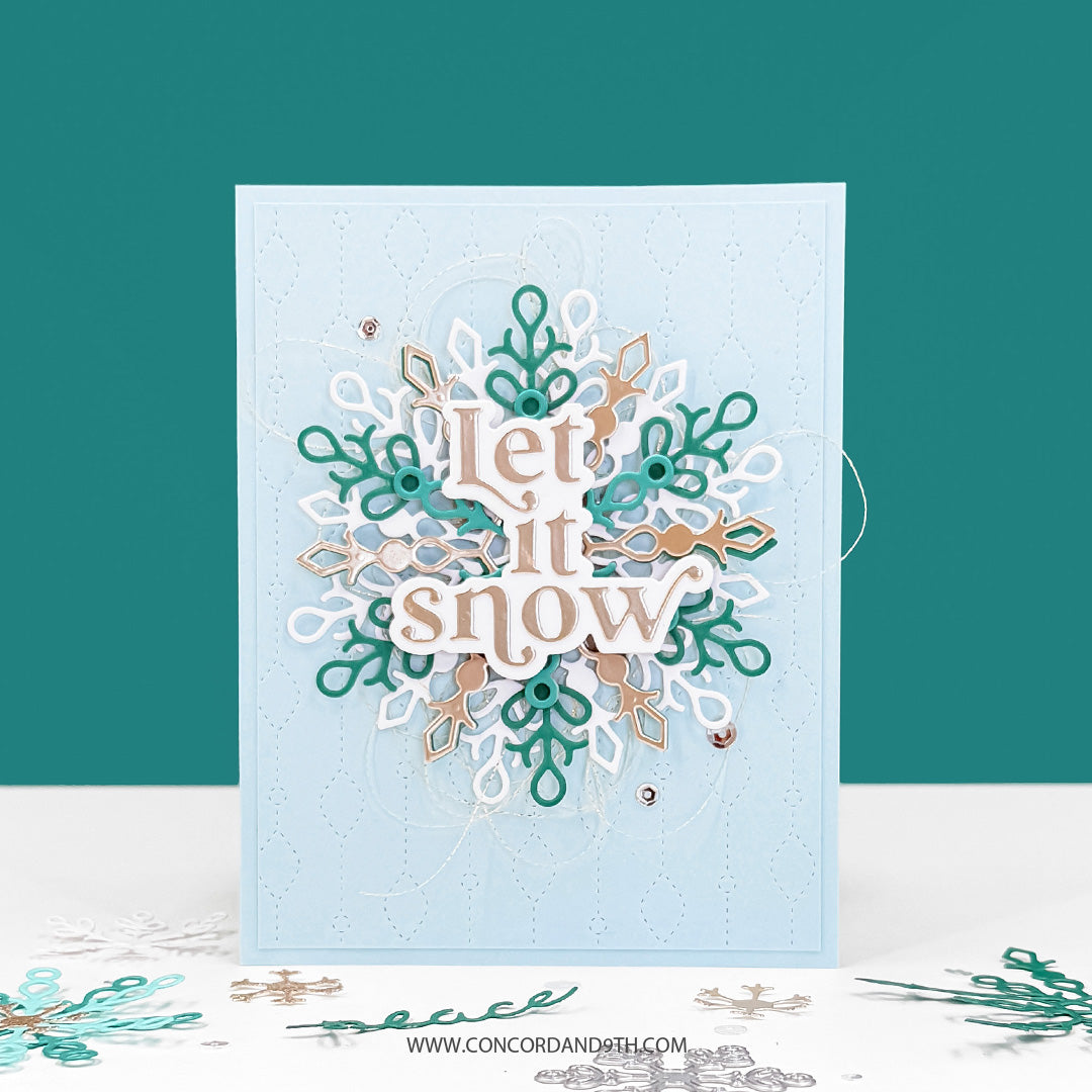 Concord & 9th Snowflake Season Dies — a large layered snowflake in white, teal and gold with a "Let it snow" sentiment, on a pale blue stitched background.