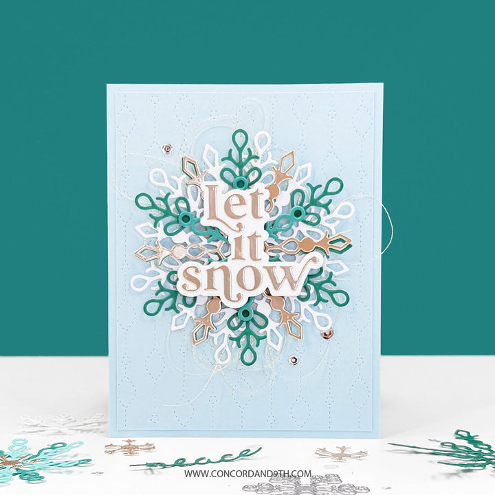 Concord & 9th Snowflake Season Dies — a large layered snowflake in white, teal and gold with a "Let it snow" sentiment, on a pale blue stitched background.