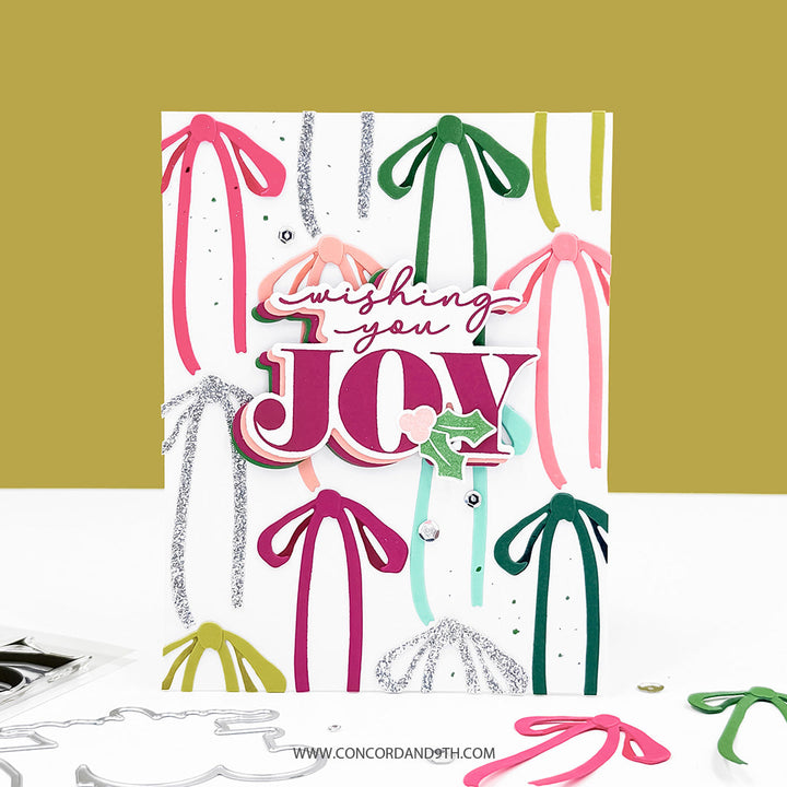 Concord & 9th Tidings of Joy Bundle — a card layered with colourful ribbon die-cuts and a "wishing you JOY" sentiment.
