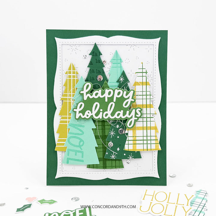 Concord & 9th Tidings of Joy Bundle — a card layered with patterned Christmas tree die-cuts, a "NOEL" stamped tree, and a "happy holidays" sentiment.