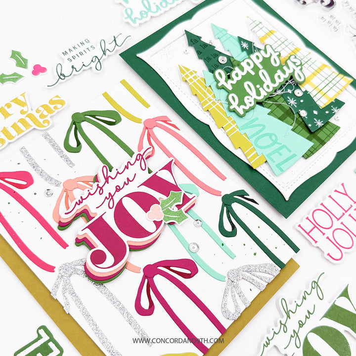 Concord & 9th Tidings of Joy Dies — the ribbon "wishing you JOY" card and the tree "happy holidays" card shown together with loose word-art stickers.