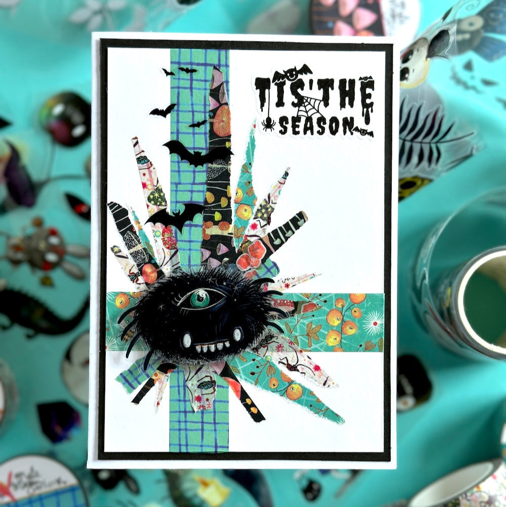 handmade card with 'Tis the Season' text surrounded by Halloween-themed decorations on a teal background.

