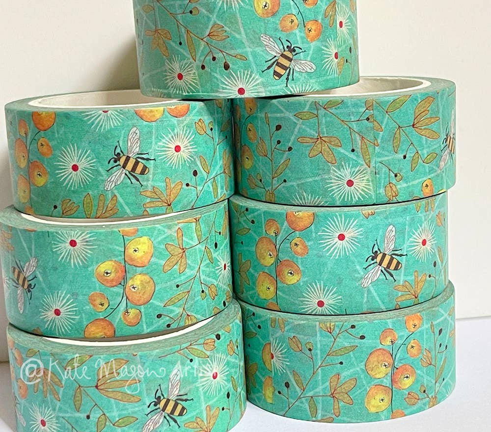 Stack of turquoise washi tape with bee and floral pattern on a white background