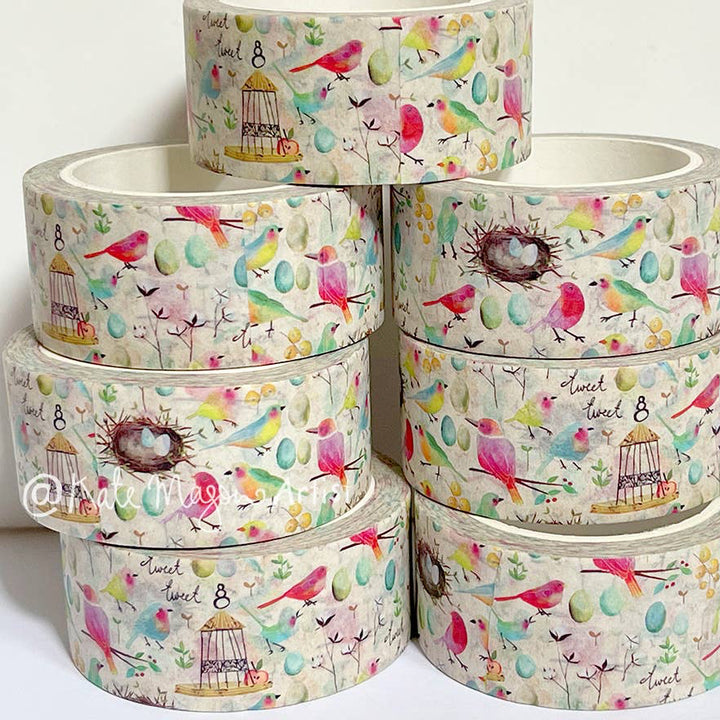 Stack of colourful Kate Mason washi tape rolls with bird and nest designs on a white background