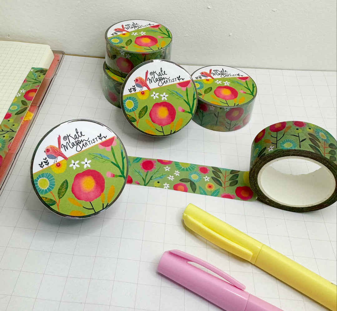 Floral-patterned tape rolls with a pink pen and yellow marker on a white surface.