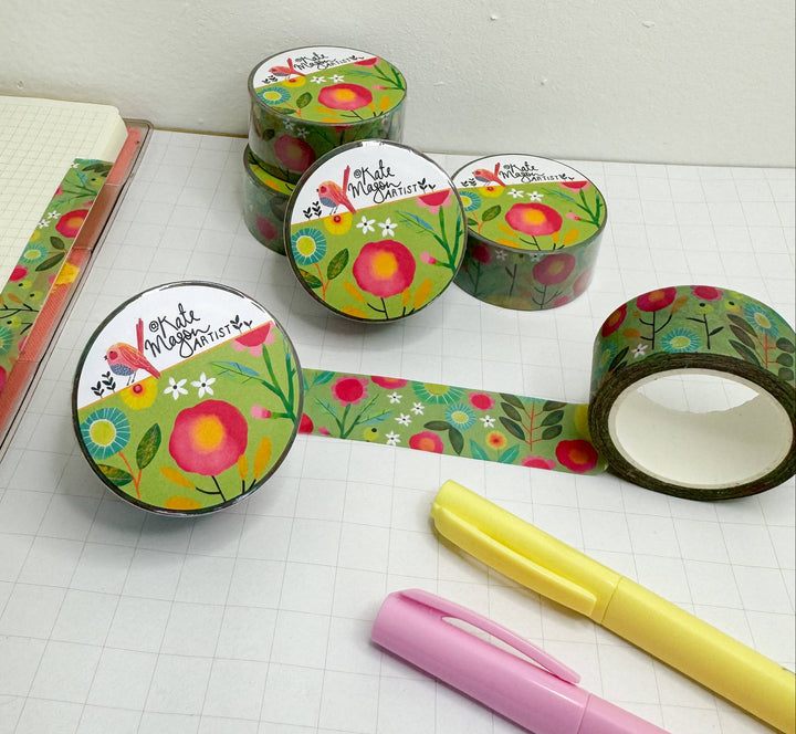Floral-patterned tape rolls with a pink pen and yellow marker on a white surface.