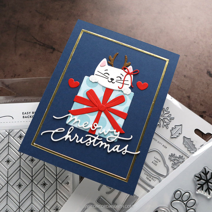 A card made with Kristina Werner's Happy Pawlidays Dies: a white cat with reindeer antlers peeks over a blue gift above 'meowy Christmas' on navy.