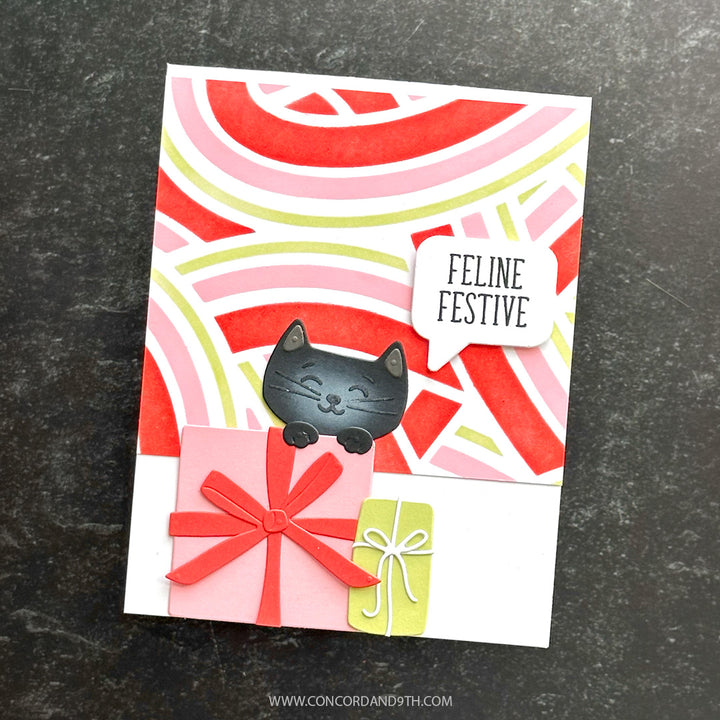 A card made with Kristina Werner's Peppermint Stripes Stencil Pack: a black cat peeks over a pink gift with a 'Feline Festive' speech bubble on candy stripes.