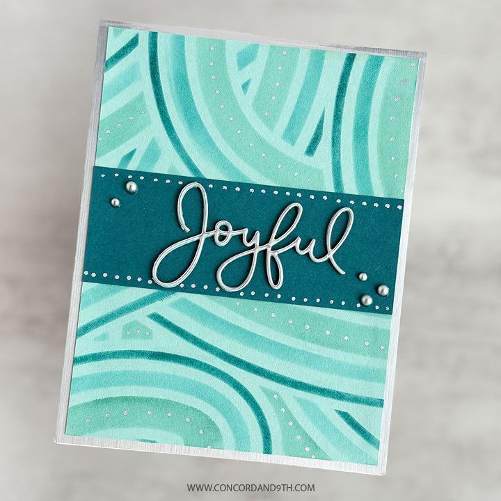 A card made with Kristina Werner's Peppermint Stripes Stencil Pack: swirling aqua and teal stripes with 'Joyful' in silver script and silver pearls.