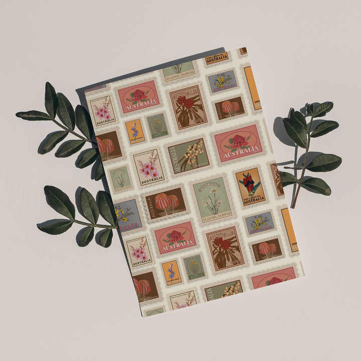 postcard with vintage stamp design on  surrounded by green leaves on a light beige background