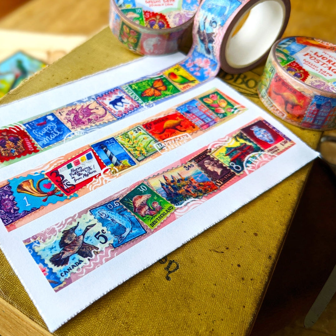 A close-up of colorful washi tape rolls and strips laid out on an old book. The tape features whimsical vintage-style illustrations, including animals, flowers, and text, with one roll showing the inner white core.