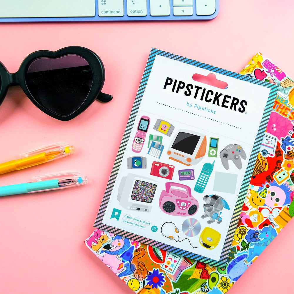 Pack of PipStickers with colorful designs on a pink surface with sunglasses and pens.