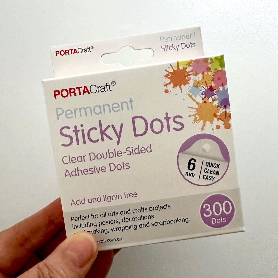 hand holding packet of adhesive sticky dots by portacraft 