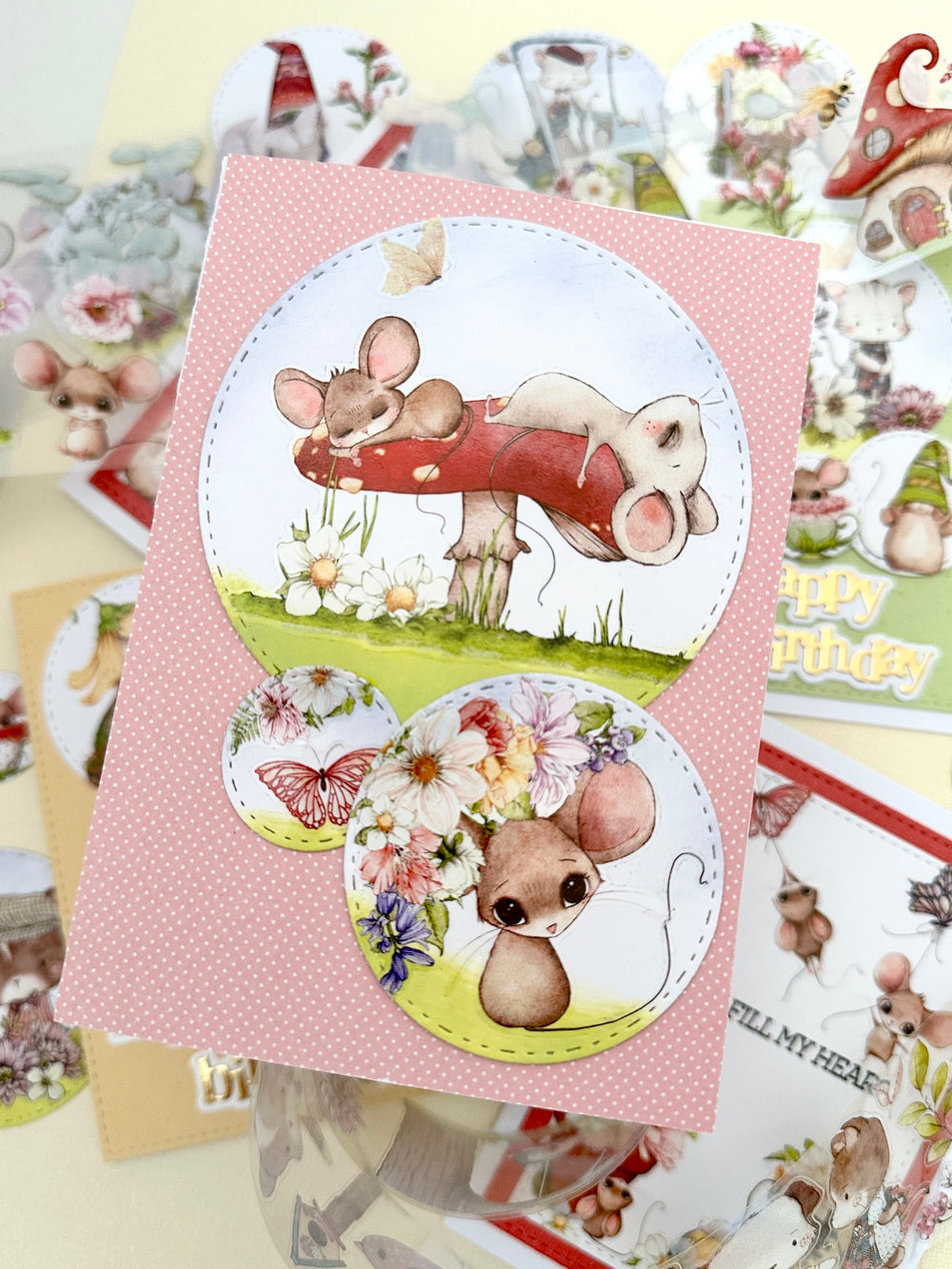 Set of cartoon mouse stickers on a pink card with more stickers in the background.