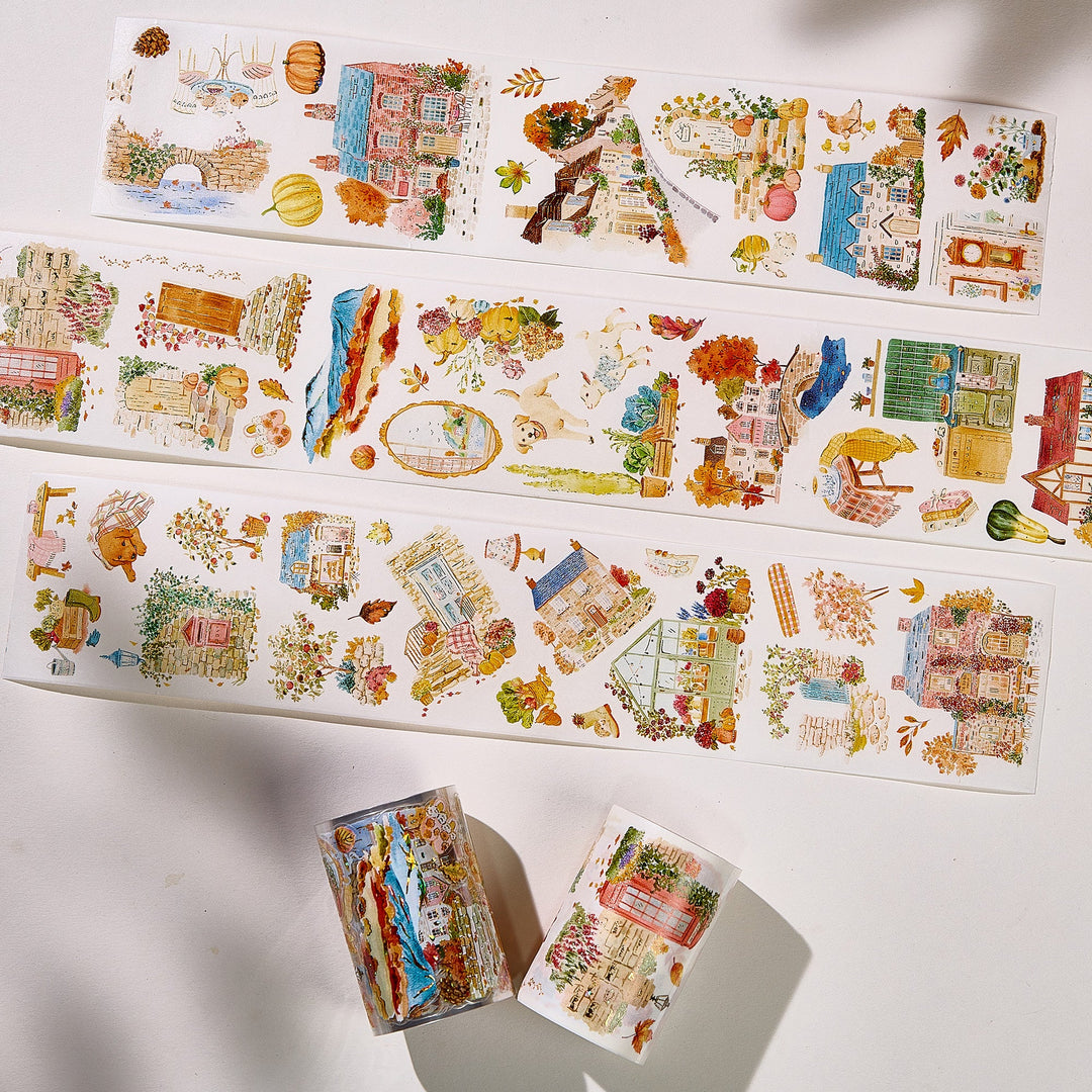 Strips of The Washi Tape Shop Autumn Village Wide Washi/PET Tape laid flat with the rolls, showing the full design