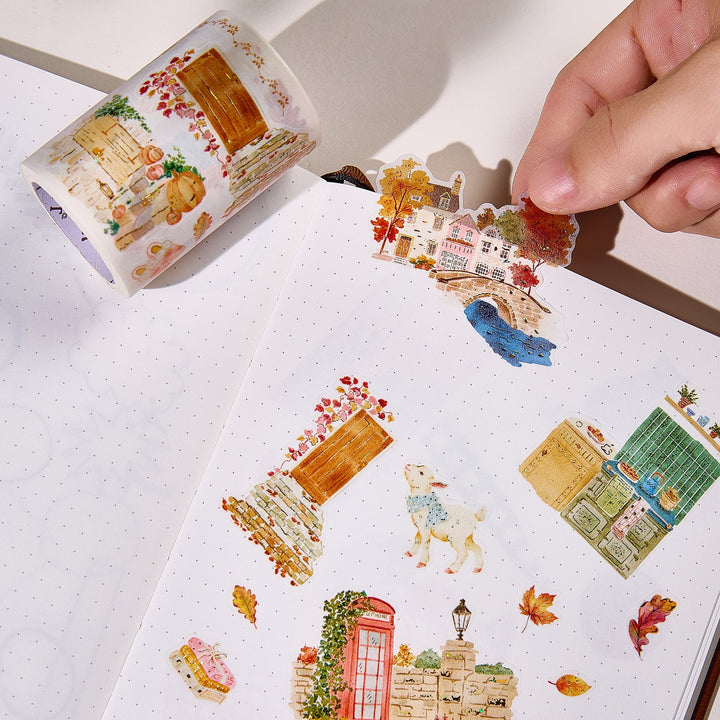 Hand peeling a pre-cut piece from The Washi Tape Shop Autumn Village Wide Washi/PET Tape onto a journal page