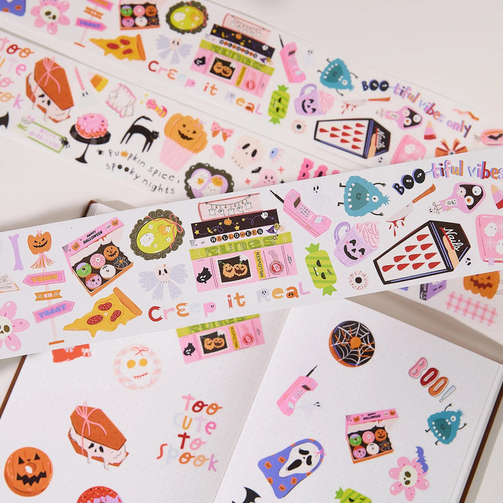 Decorative washi tape with colourful Halloween-themed illustrations, including pumpkins, ghosts, spiders, candy corn, and spooky buildings, arranged on a white surface.
