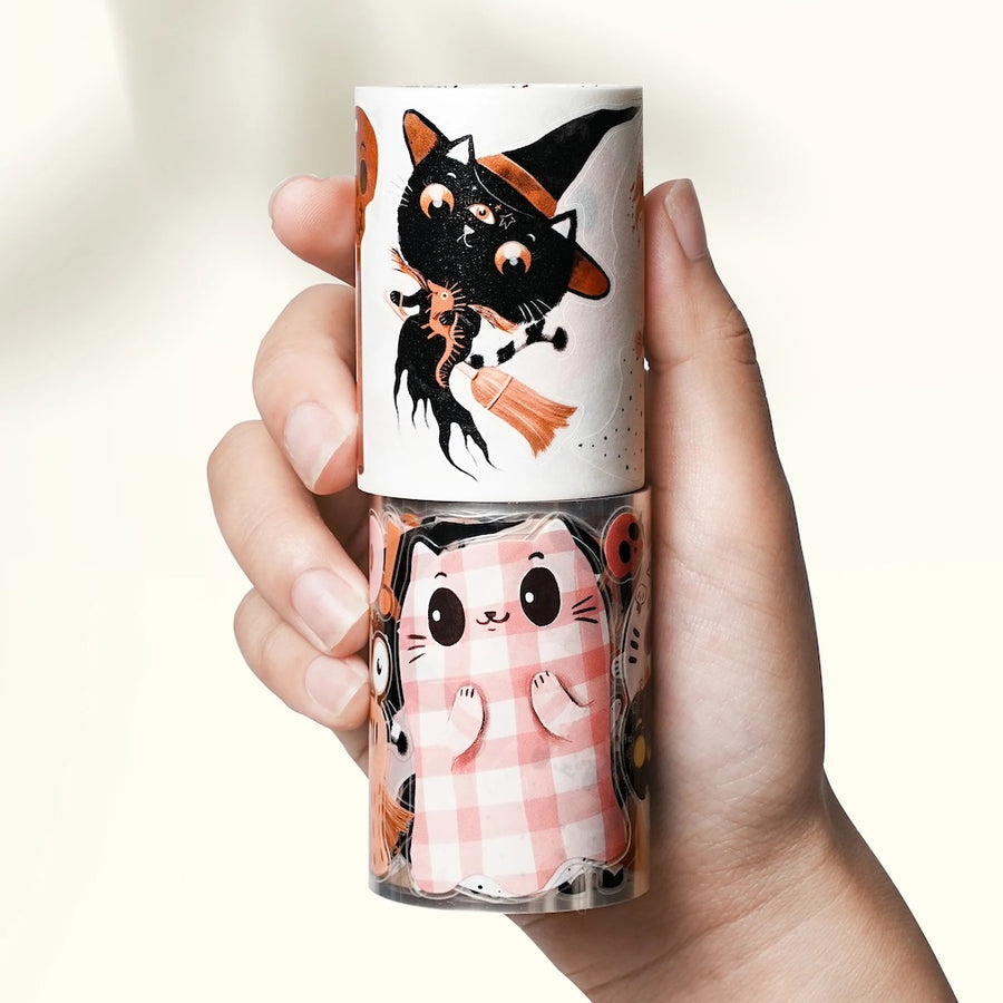 Hand holding a washi and PET tapes with Halloween themed  illustrations on a white background