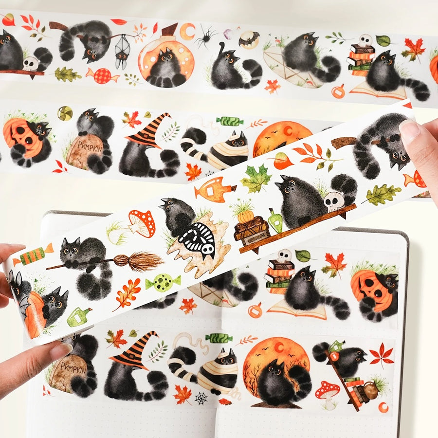 Halloween-themed precut washi with cats and autumn elements held by a person.