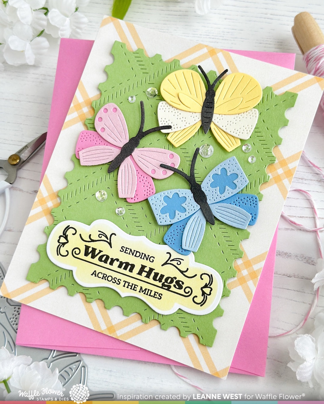 Greeting card with colorful butterflies and text 'Sending Warm Hugs Across the Miles' on a white background.