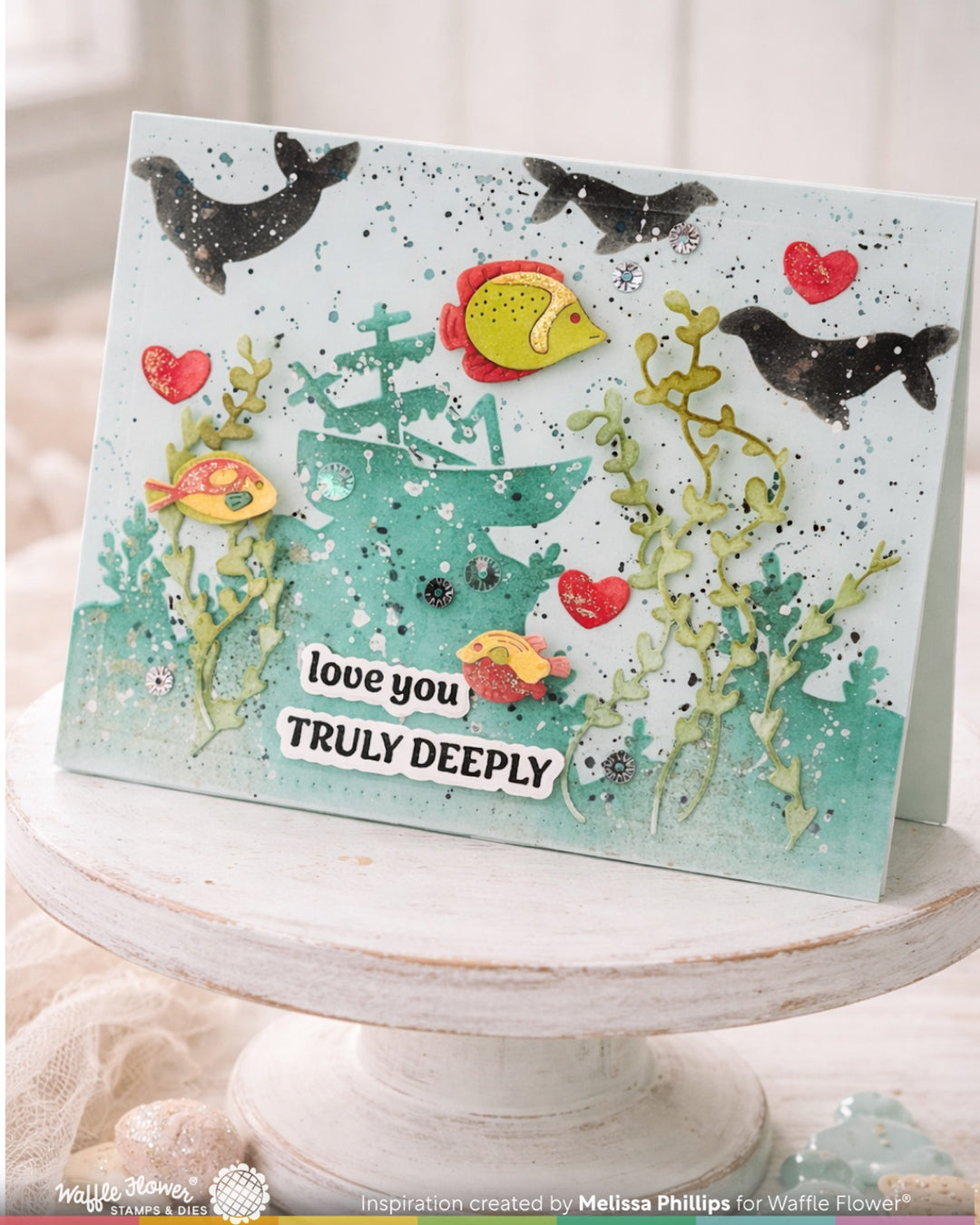 Card with underwater scene, fish, and coral with 'love you truly deeply' text on a white stand.