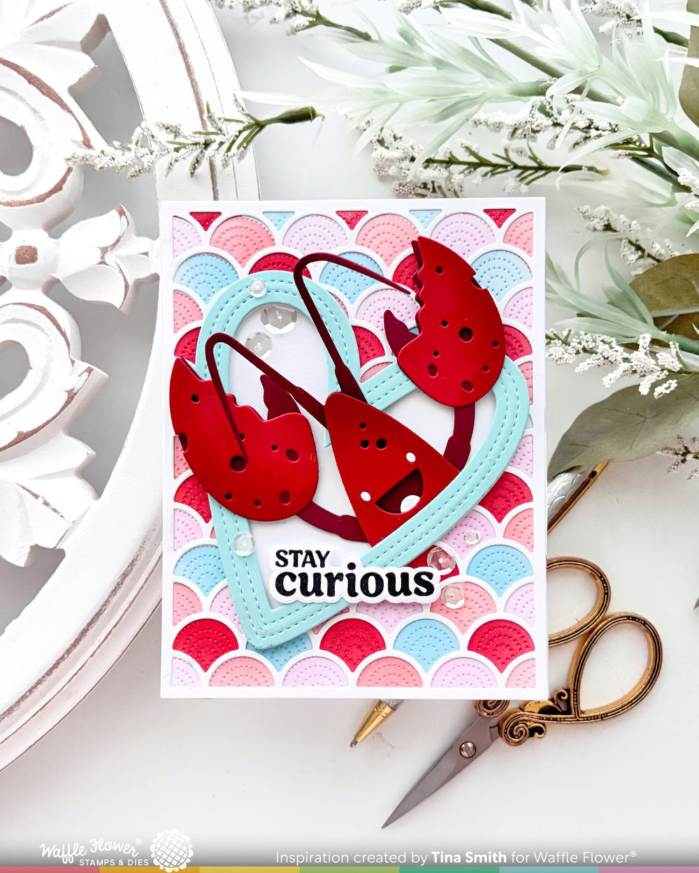 Card with red lobster and 'Stay curious' text on a decorative background with flowers and scissors.