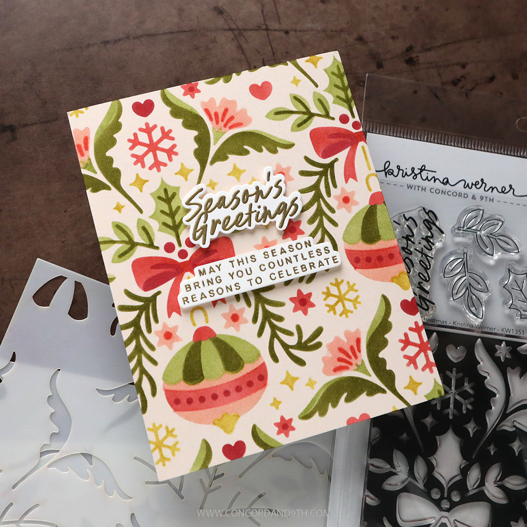 Concord & 9th Kristina Werner Holiday Cheer Greetings Dies — a "Season's Greetings" card on a cream floral and ornament patterned background.