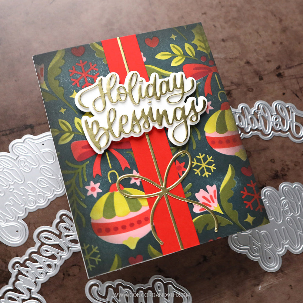Concord & 9th Kristina Werner Holiday Hugs and Blessings Dies — a "Holiday Blessings" script die on a festive ornament and floral patterned background with a red ribbon and gold wire bow.