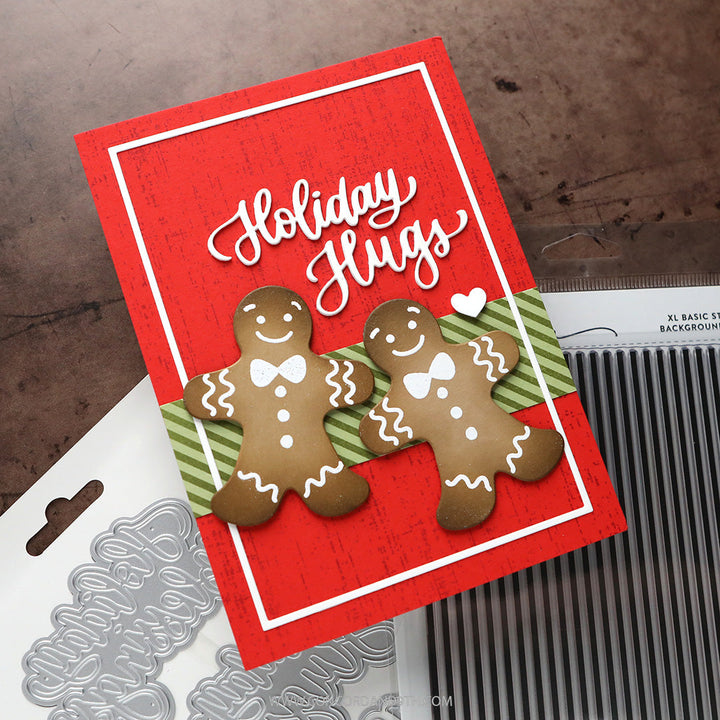 Concord & 9th Kristina Werner XL Basic Stripes Background Stamp — a red "Holiday Hugs" card with two gingerbread man die-cuts on a striped green ribbon.
